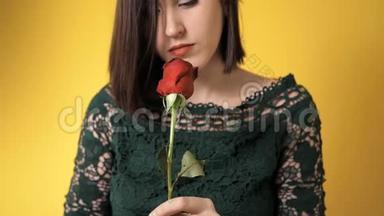 <strong>红</strong>玫瑰的女孩若有所思地嗅着<strong>黄色背景</strong>下美丽的花朵。 2月14日情人节，生日